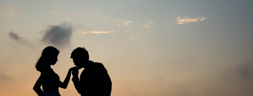 silhouette of man kissing hand of woman