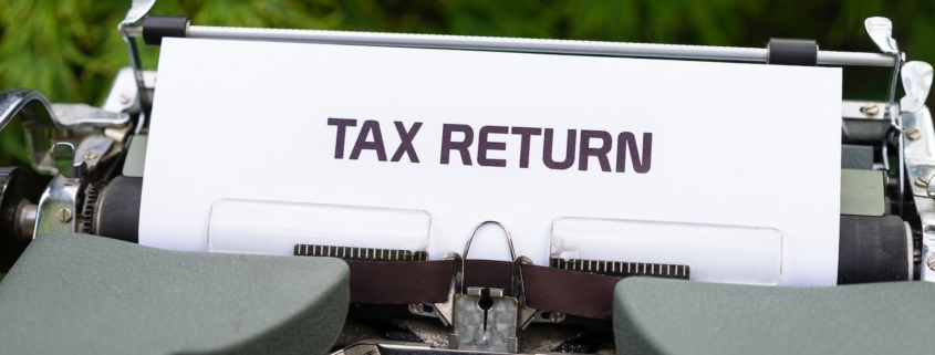 a close up of a typewriter with a tax return sign on it