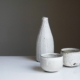 two white ceramic bowls and bottle on white table