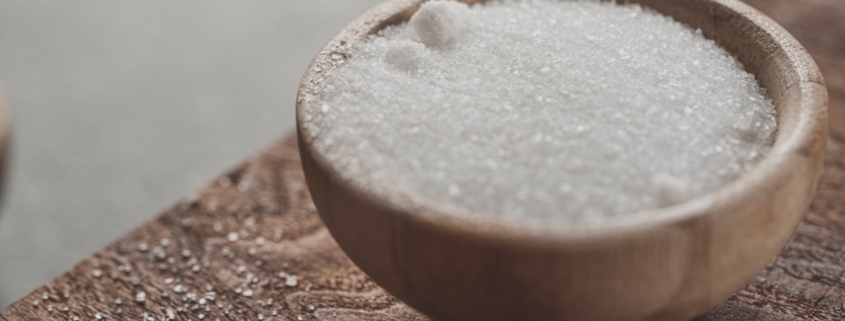 a wooden bowl filled with sugar on top of a wooden table